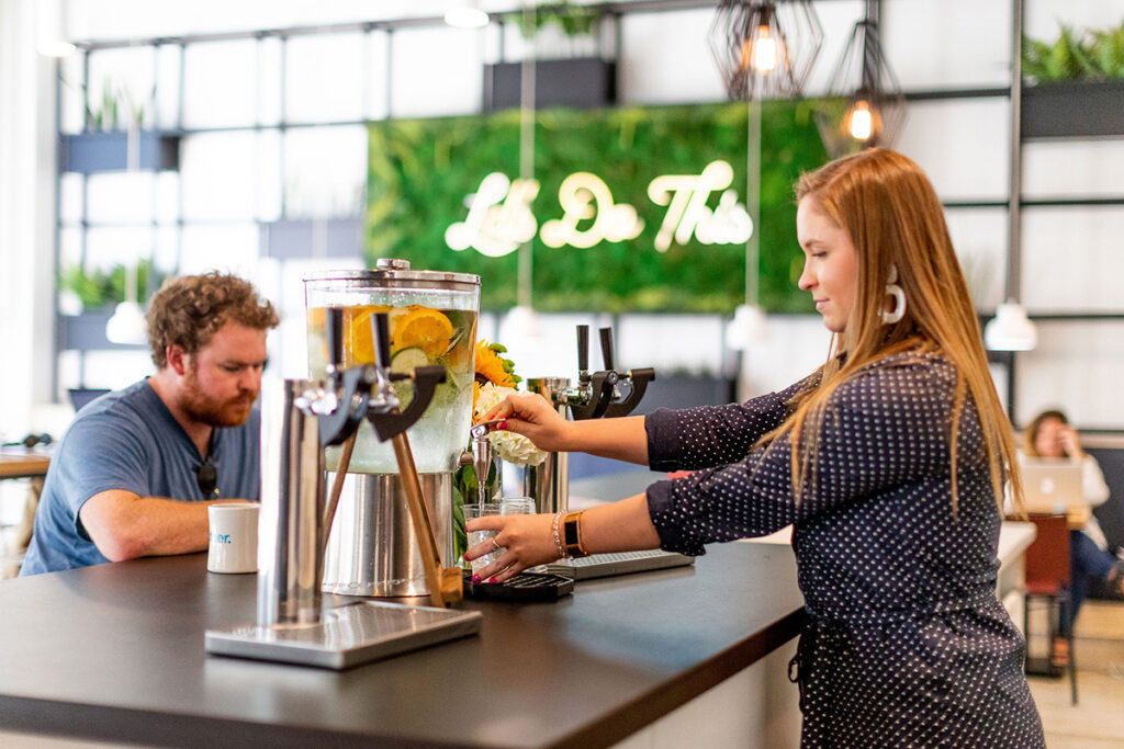 Woman fills a glass from a citrus-infused water dispenser in a modern kitchen at Short Pump, Glen Allen, VA
