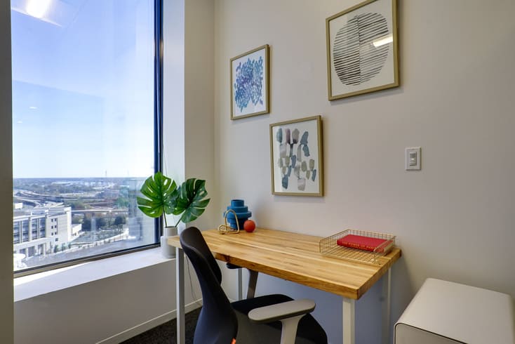 Private office workspace with wood desk, ergonomic chair, and large window view at Gather Workspaces