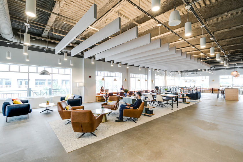 Bright open coworking lounge at Gather Workspaces with seating area, shared desks, and modern lighting