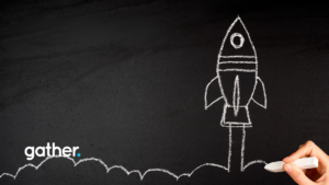 A hand drawing a rocket ship blasting off on a chalkboard.