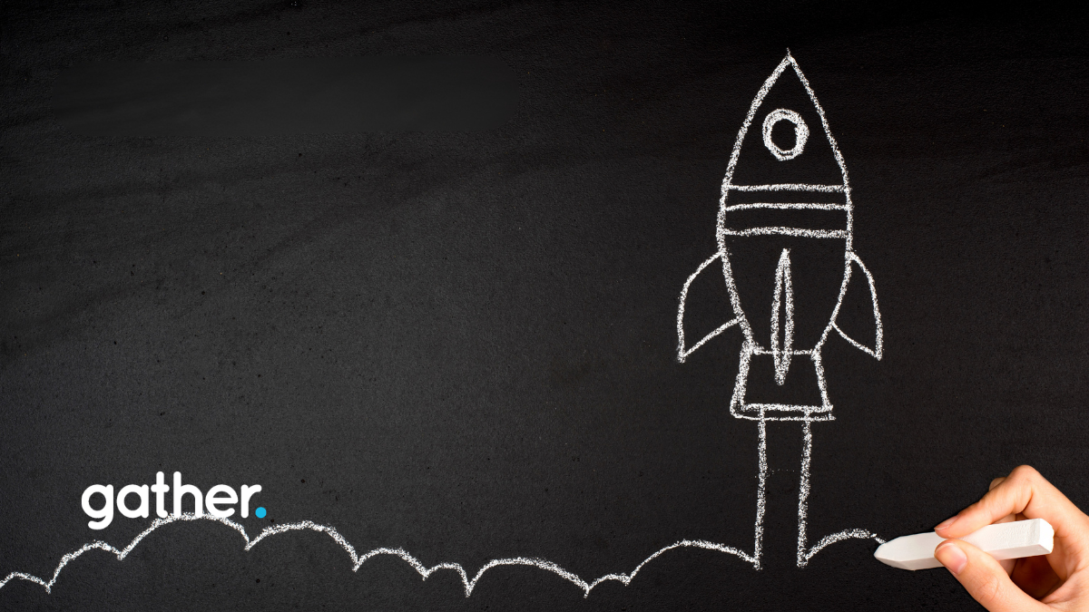 A hand drawing a rocket ship blasting off on a chalkboard.
